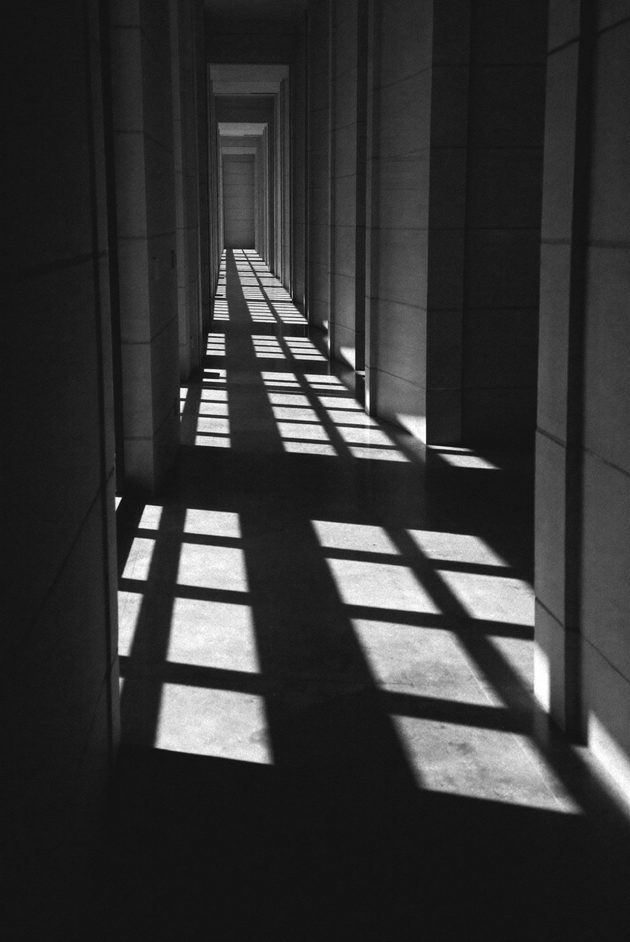 A silhouetted figure walking through a bright doorway, extreme backlight, dust in the air