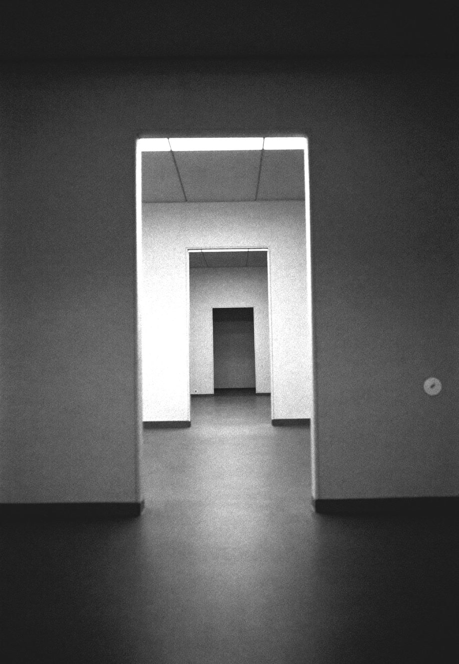 A glass partition catching hard light, minimal interior, abstract reflection