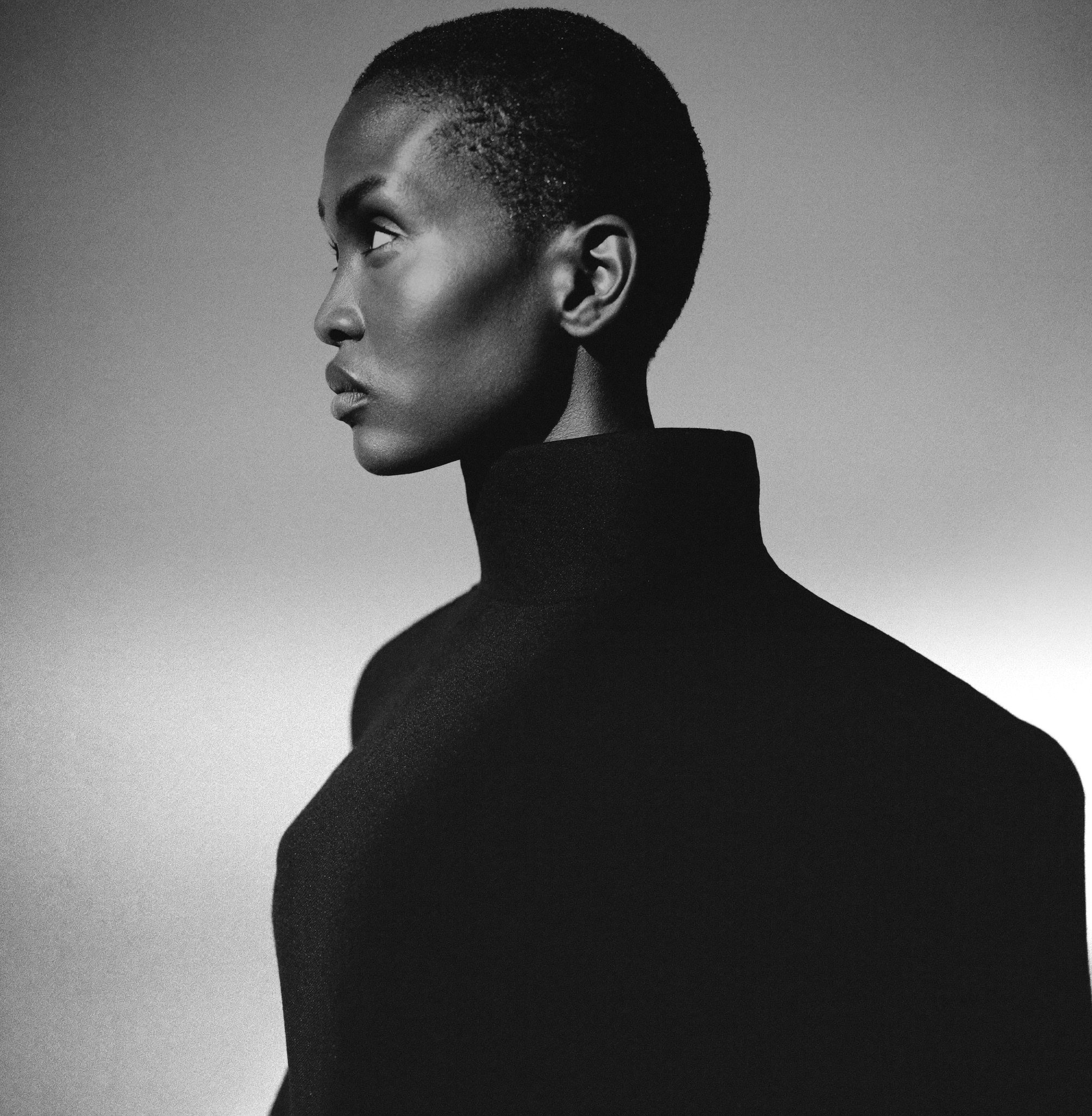 Black and white studio portrait of a figure in a sculptural high-neck garment, Promot Egypt hero image