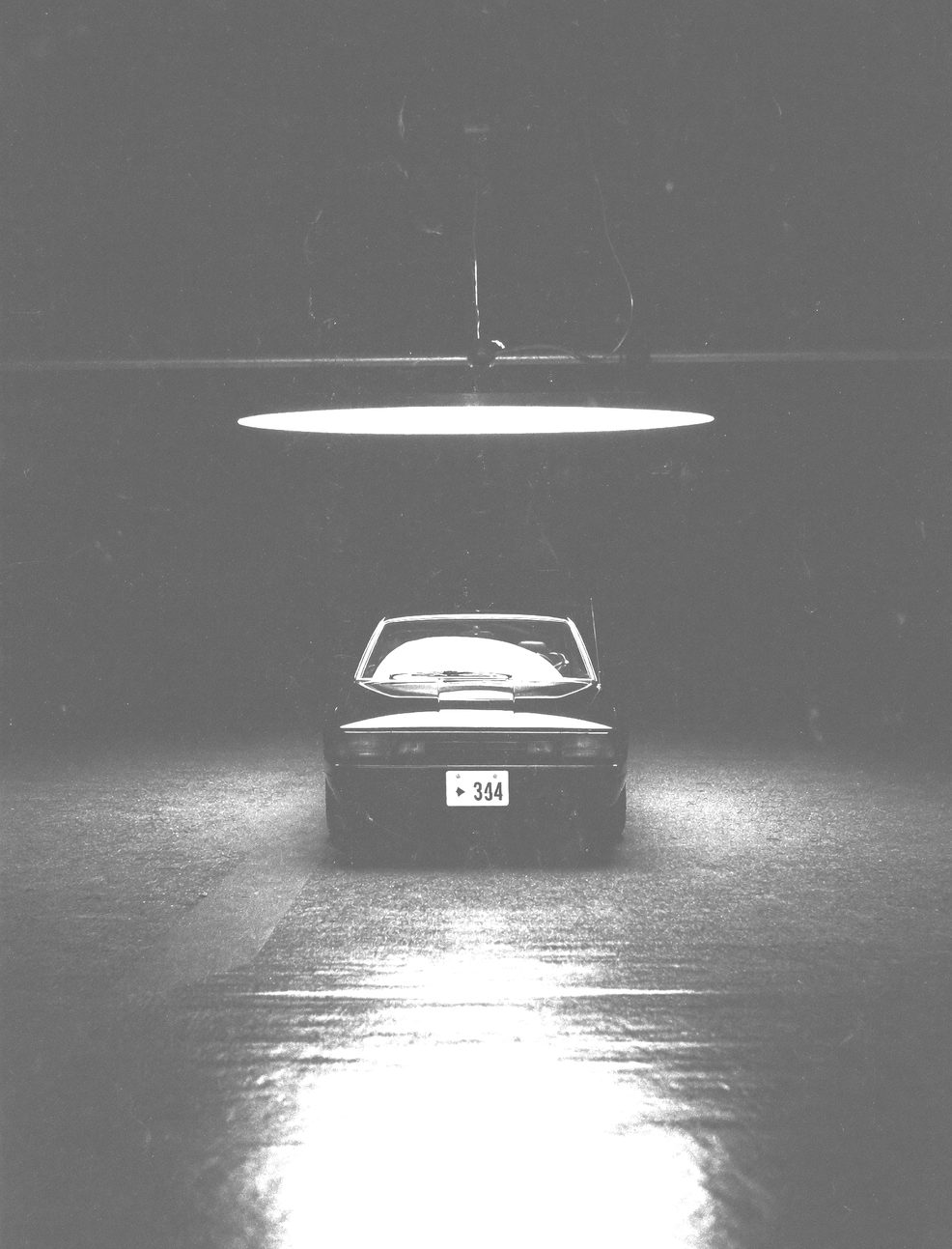 Silhouette of a car under a concrete overpass with hard shafts of light