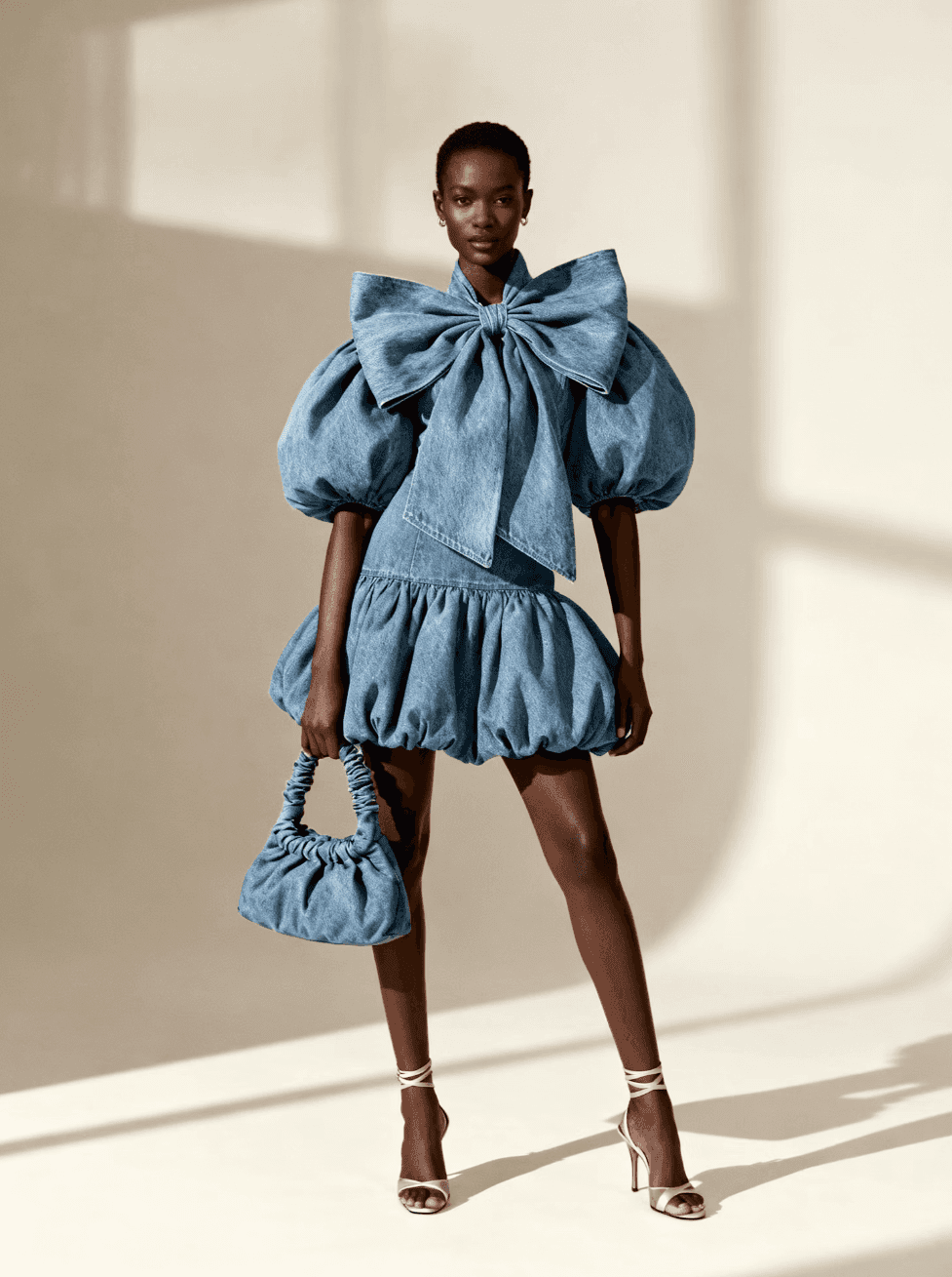 Woman in a blue puff-sleeve mini dress with a matching bag