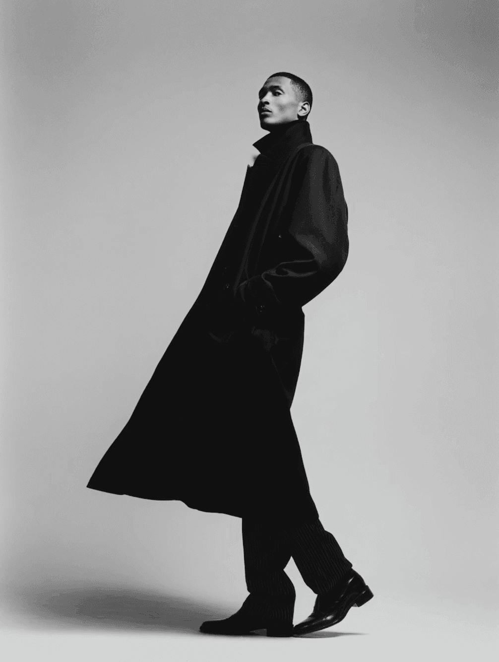 Full-length figure in a long dark coat walking